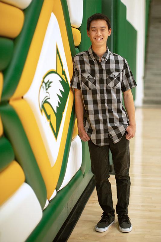 Troy Makalena leaning against a wall with the CUI Eagles logo